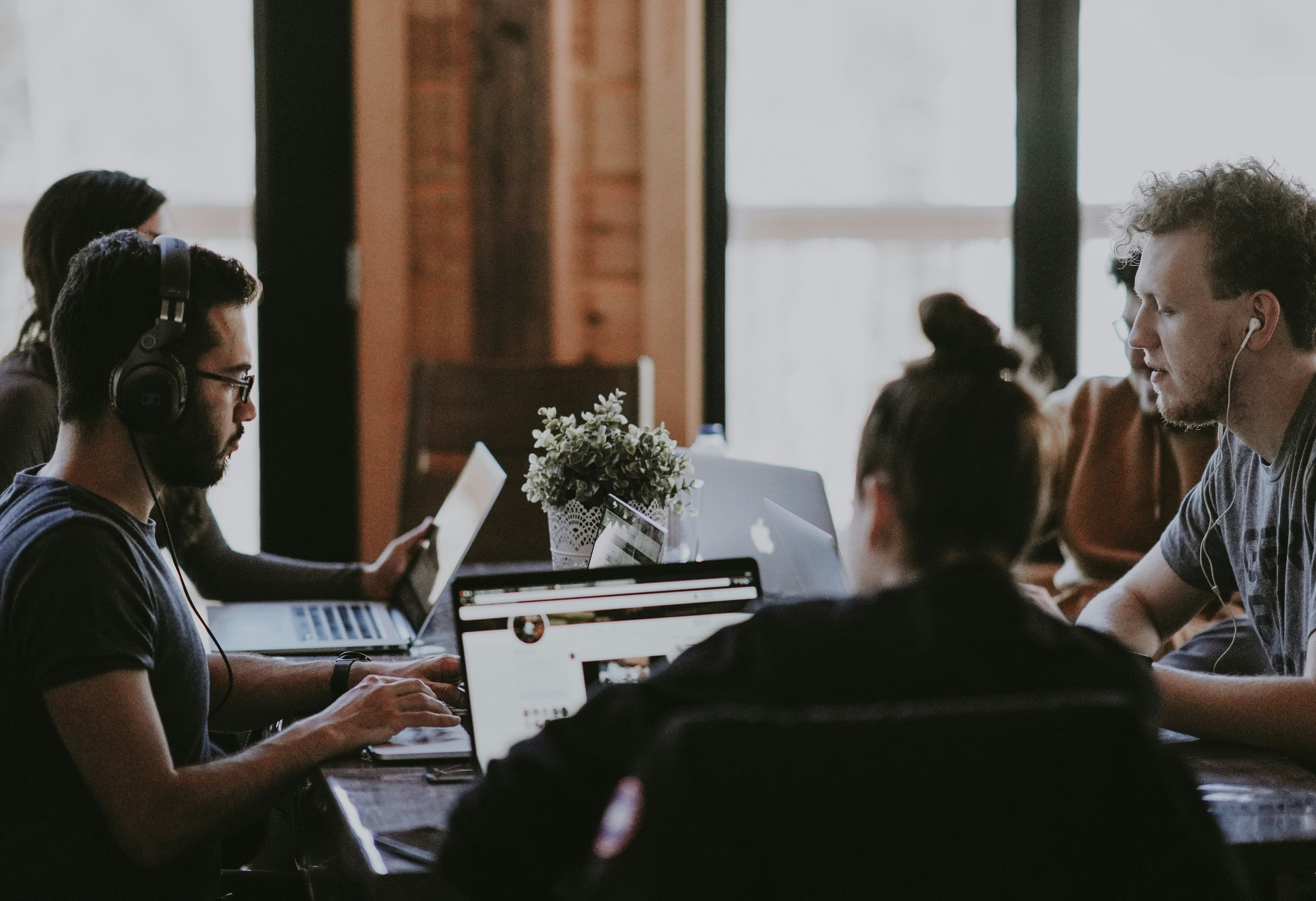 Team collaborating with laptops and headphones in a studio workspace